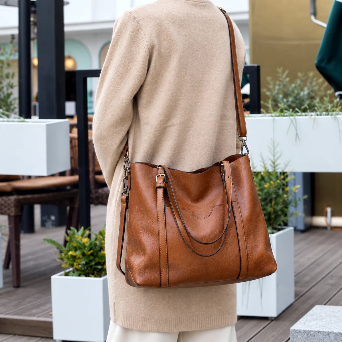 Woman carrying the Eleonora tote on her shoulder on a cafe terrace